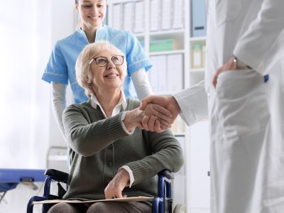 Elderly woman shaking hands with a doctor.
